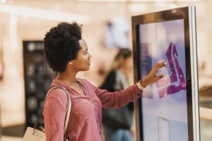 Person interacting with a touchscreen mall directory in a public indoor space