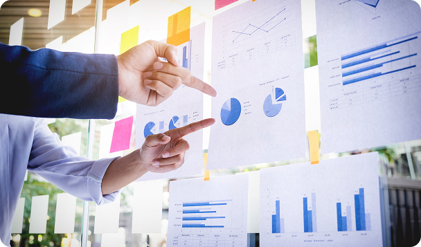 Hands pointing at printed charts and graphs on wall