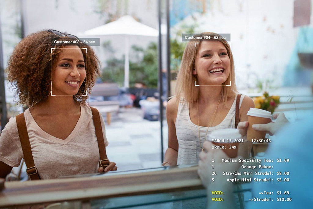 Two customers at a quick service restaurant counter with order details displayed
