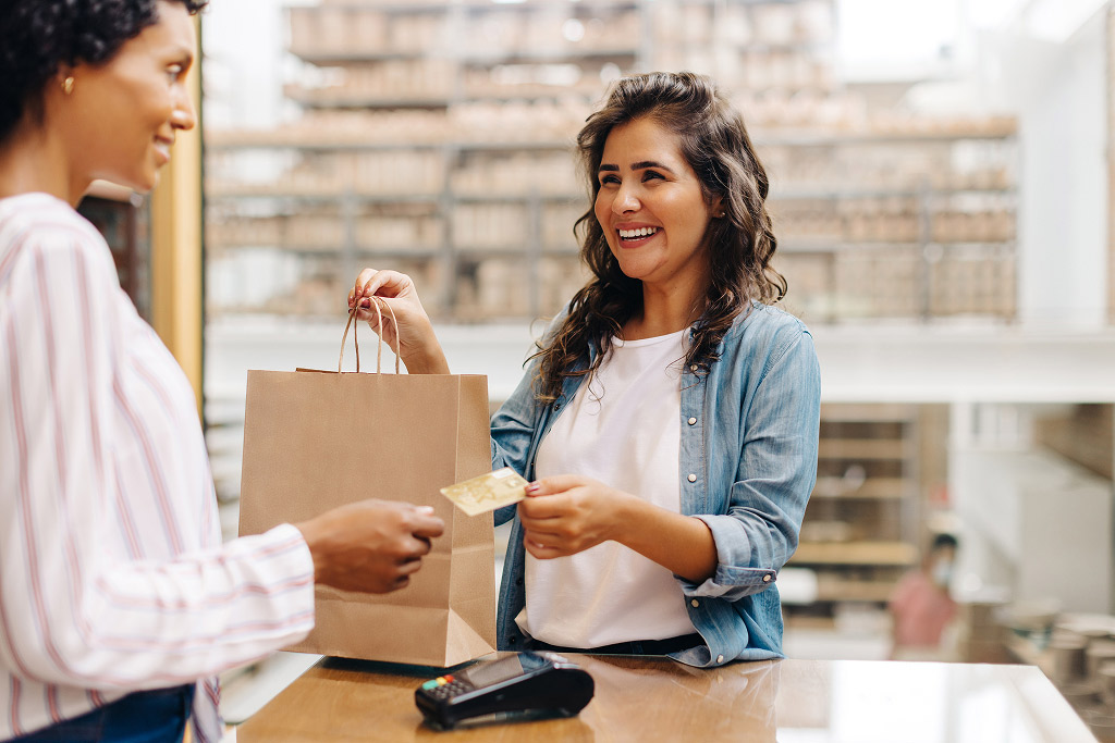Customer making a purchase at a thrift store counter with a shopping bag and payment card