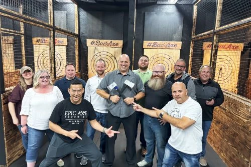 Group posing at axe-throwing venue with wooden targets