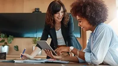 Two people collaborating at a desk with tablet and documents