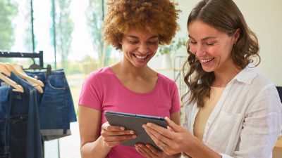 Two people in a clothing store looking at a tablet together