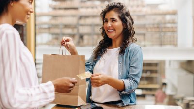 Customer making a purchase at a thrift store counter with a shopping bag and payment card